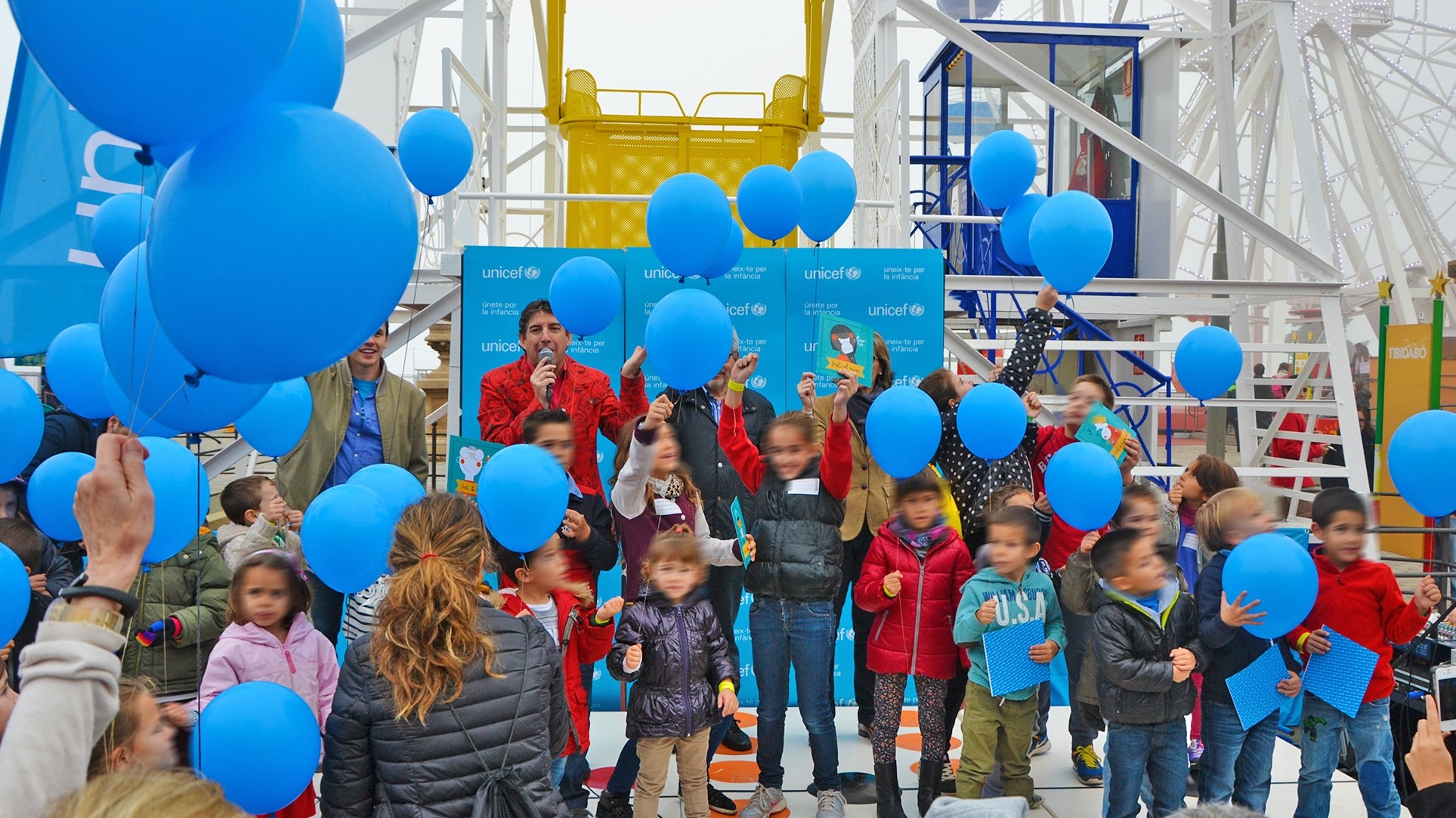 Celebració d'una festa d'Unicef, plena de nens i globus blaus, al Parc d'Atraccions Tibidabo