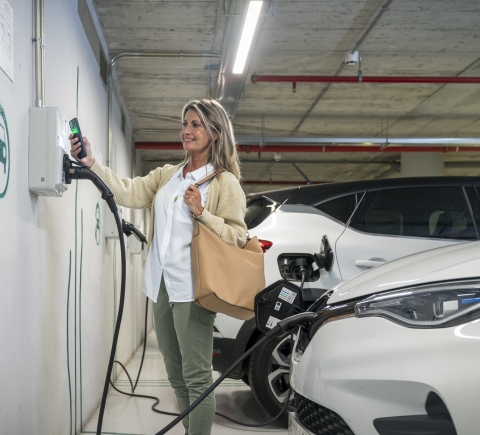Una mujer poniendo a cargar su coche eléctrico en la red Endolla Barcelona dentro de un Aparcamiento B:SM