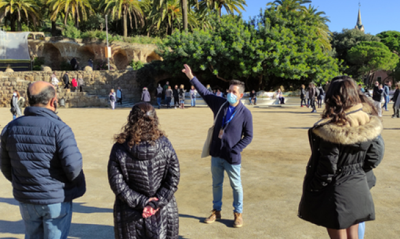 Guia oficial del Park Güell fent una explicació a tres visitants gràcies al servei de visites comentades