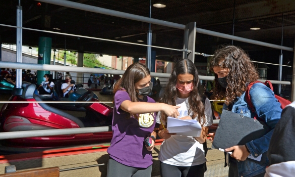 Tres noies revisant un document davant una atracció del Tibidabo