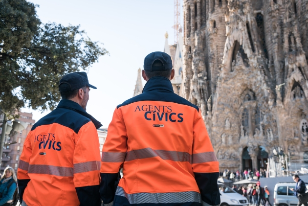 Dos agentes cívicos en horario de servicio delante de la Sagrada Família velando por la convivencia en espacios de gran afluencia  