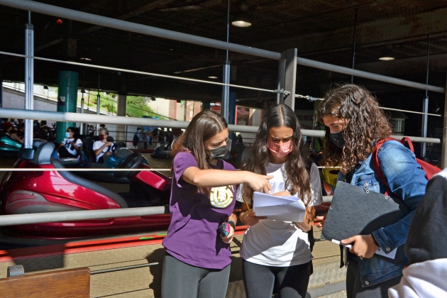 Tres noies revisant un document davant una atracció del Tibidabo