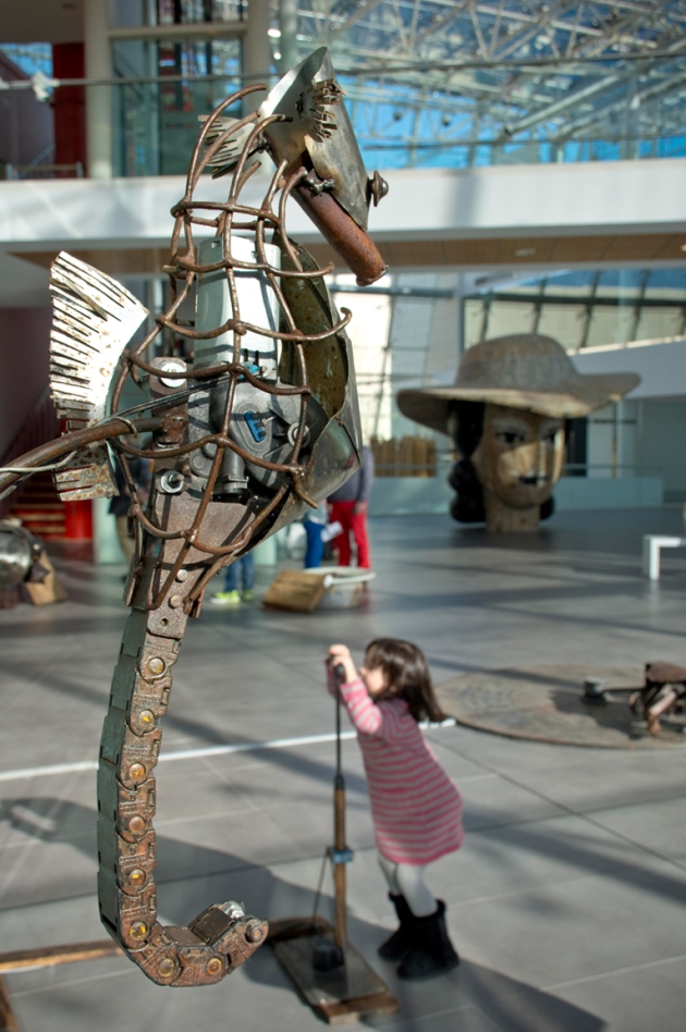 Una nena mirant a un cavallet de mar fet de ferro